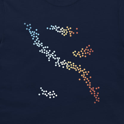 A close-up of a navy blue t-shirt featuring a stylized graphic of a fish made of white, yellow, orange, and red gradient dots.