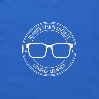 A close-up of a royal blue t-shirt featuring a white distressed graphic of glasses inside a circular seal with the text 'BLURRY VISION SOCIETY' and 'CHARTER MEMBER'.