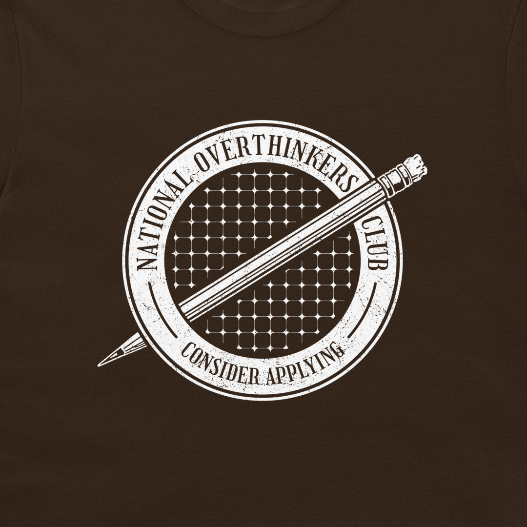 A close-up of a dark brown t-shirt featuring a white distressed graphic of a pencil inside a circular emblem that reads 'NATIONAL OVERTHINKERS CLUB' and 'CONSIDER APPLYING'.