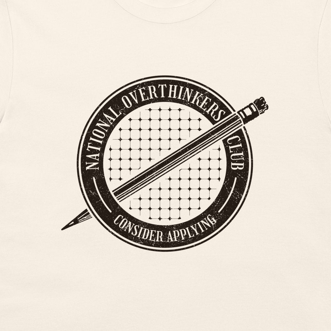 A close-up of a cream-colored t-shirt featuring a distressed black circular graphic with a pencil and the text 'NATIONAL OVERTHINKERS CLUB' and 'CONSIDER APPLYING'.