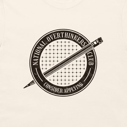 A close-up of a cream-colored t-shirt featuring a distressed black circular graphic with a pencil and the text 'NATIONAL OVERTHINKERS CLUB' and 'CONSIDER APPLYING'.