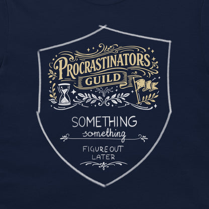 A close-up of a navy blue t-shirt featuring a white and gold graphic print on the chest. The graphic is a shield-shaped emblem with the text 'PROCRASTINATORS GUILD' in gold and white, and 'SOMETHING FIGURE OUT LATER' in white below it.