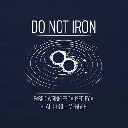 A close-up of a navy blue t-shirt, featuring a white graphic print of a black hole merger with the text 'DO NOT IRON' and 'FABRIC WRINKLES CAUSED BY A BLACK HOLE MERGER'.