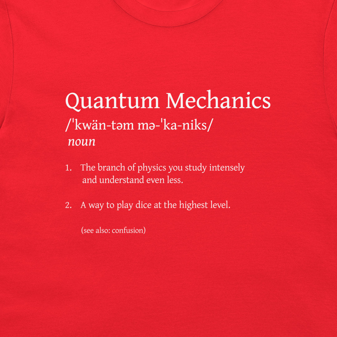 A close-up of a bright red t-shirt featuring white printed text that defines 'Quantum Mechanics' in a dictionary style with humorous, nonsensical dictionary entries.