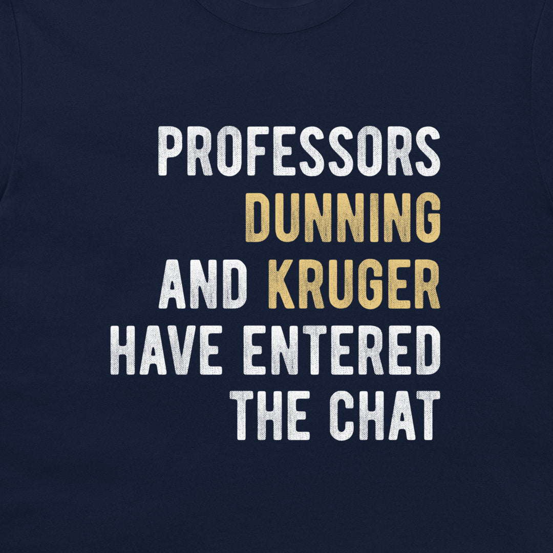 A close-up of a navy blue t-shirt featuring a humorous text graphic in white and gold lettering that reads 'PROFESSORS DUNNING AND KRUGER HAVE ENTERED THE CHAT'.