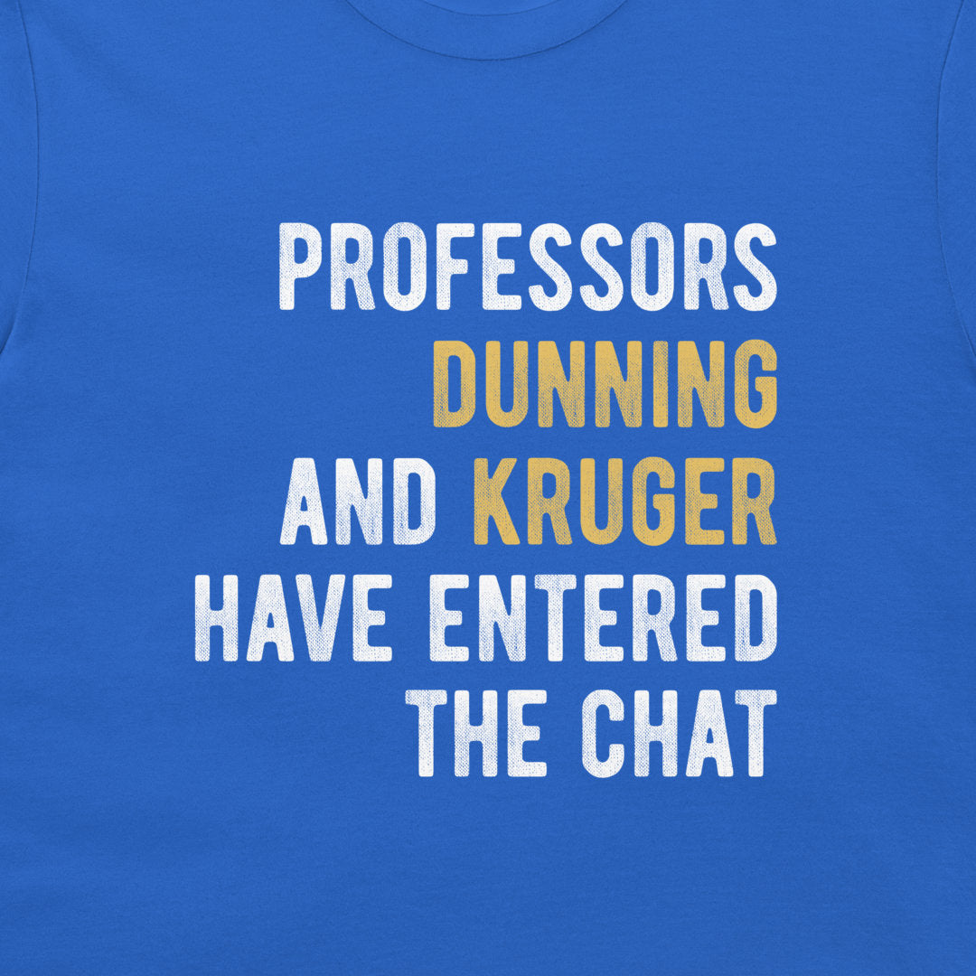A close-up of a royal blue t-shirt featuring a typographic graphic that reads 'PROFESSORS DUNNING AND KRUGER HAVE ENTERED THE CHAT' in bold white and mustard yellow lettering.