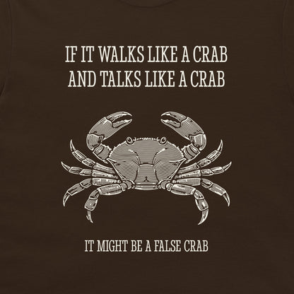 A dark brown graphic print on a t-shirt featuring a white line art illustration of a crab and the humorous text 'IF IT WALKS LIKE A CRAB AND TALKS LIKE A CRAB IT MIGHT BE A FALSE CRAB'.