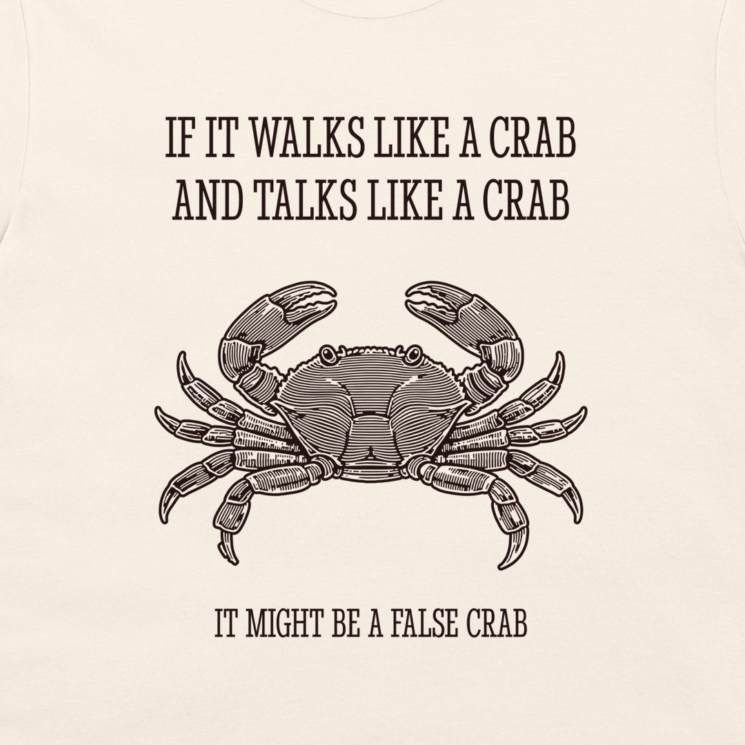 A close-up of a cream-colored garment, likely a t-shirt, featuring a black graphic print of a crab and the humorous text 'IF IT WALKS LIKE A CRAB AND TALKS LIKE A CRAB IT MIGHT BE A FALSE CRAB'.