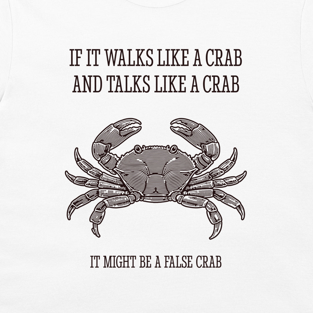 A white graphic t-shirt featuring a black line art illustration of a crab with the humorous text 'IF IT WALKS LIKE A CRAB AND TALKS LIKE A CRAB IT MIGHT BE A FALSE CRAB'.
