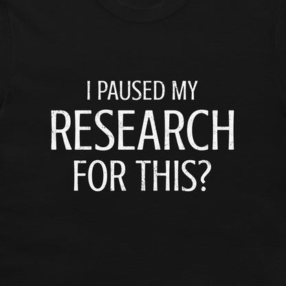 A close-up of a black t-shirt featuring the text 'I PAUSED MY RESEARCH FOR THIS?' printed in a distressed white sans-serif font.