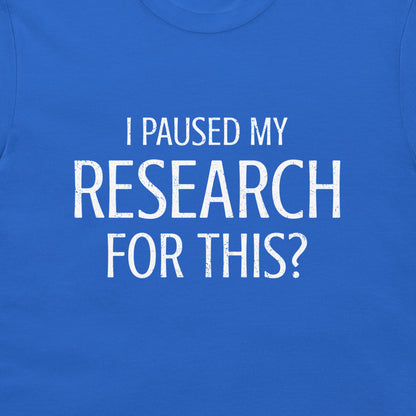 A close-up of a royal blue t-shirt featuring the text 'I PAUSED MY RESEARCH FOR THIS?' printed in a distressed white sans-serif font across the chest.