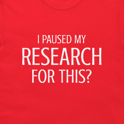 A close-up of a bright red t-shirt featuring the text 'I PAUSED MY RESEARCH FOR THIS?' printed in a distressed white sans-serif font across the chest.