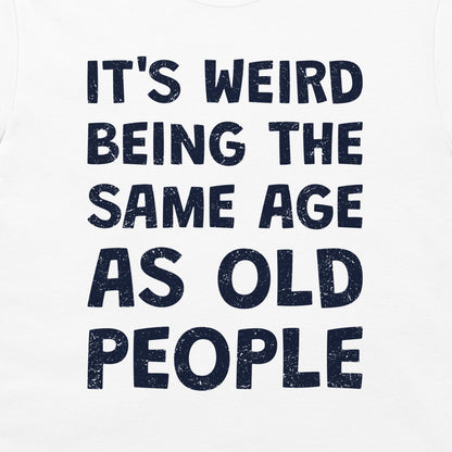 White t-shirt with a dark navy blue distressed text graphic that reads 'IT'S WEIRD BEING THE SAME AGE AS OLD PEOPLE'.