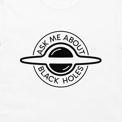 A close-up of a white t-shirt, featuring a black circular graphic of a ringed black hole with the text 'ASK ME ABOUT BLACK HOLES' printed on it.