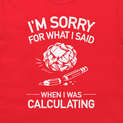 A close-up of a red t-shirt, featuring a white distressed graphic print that reads 'I'M SORRY FOR WHAT I SAID WHEN I WAS CALCULATING' with an illustration of a broken brain and pencil.