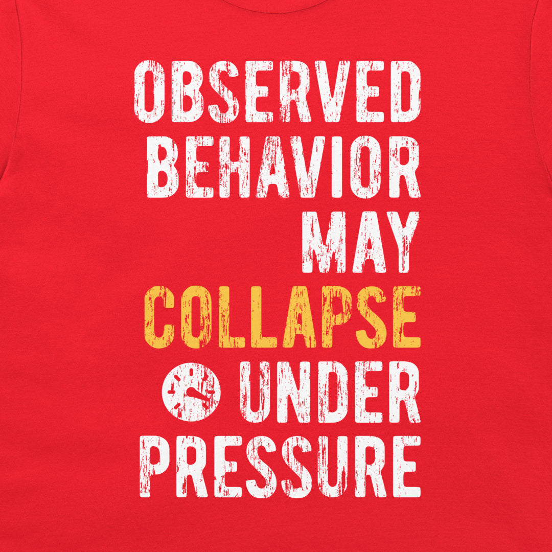 A close-up of a red shirt or fabric panel with large distressed white text reading 'OBSERVED BEHAVIOR MAY COLLAPSE UNDER PRESSURE' and a small clock icon, with 'COLLAPSE' highlighted in yellow.
