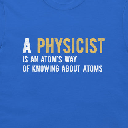 A close-up of a blue t-shirt featuring a printed graphic with the text 'A PHYSICIST IS AN ATOM'S WAY OF KNOWING ABOUT ATOMS' in white and yellow lettering.