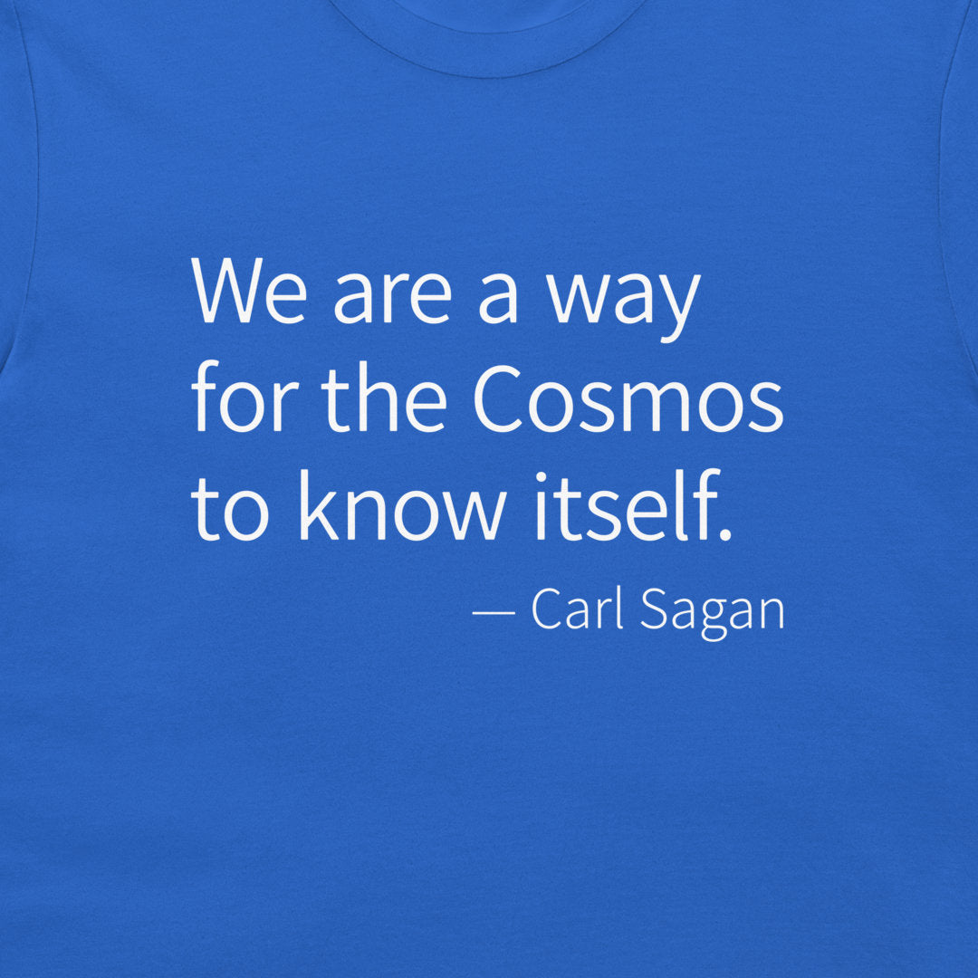 A close-up of a blue T-shirt with a white printed quote that reads, 'We are a way for the Cosmos to know itself. — Carl Sagan'.