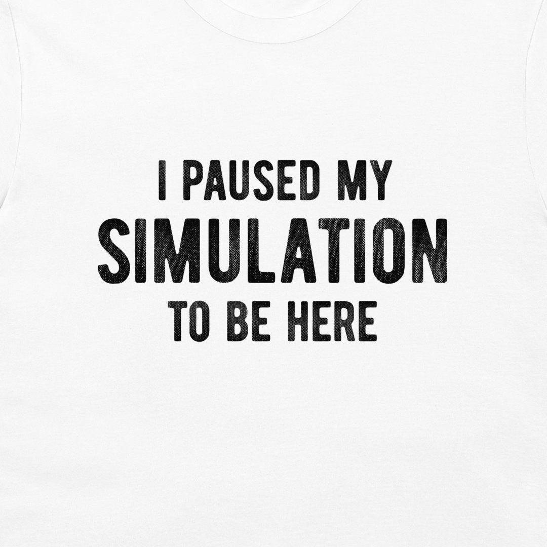 White t-shirt with black distressed text reading 'I PAUSED MY SIMULATION TO BE HERE' on the front.