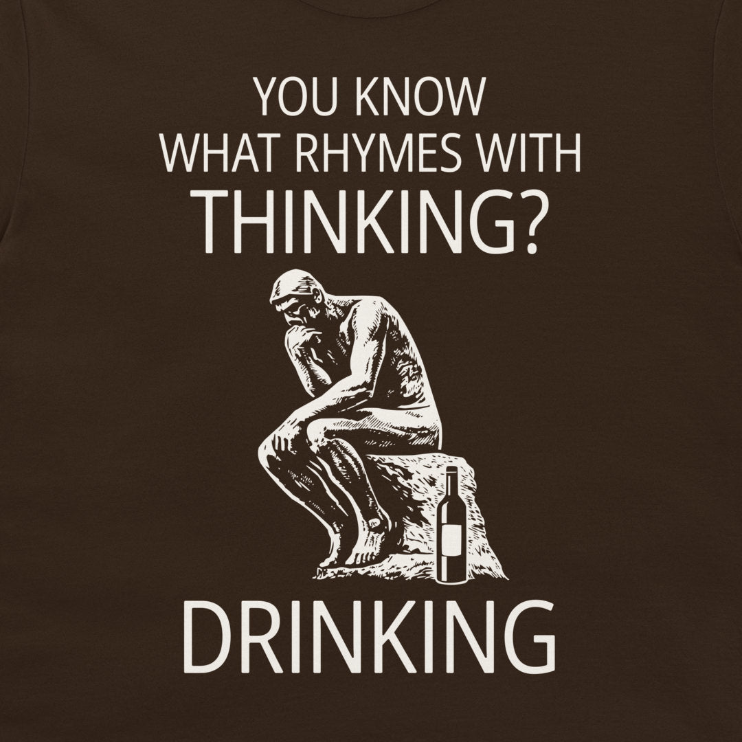 A dark brown t-shirt featuring a white graphic print of the Thinker statue next to a wine bottle, with the text 'YOU KNOW WHAT RHYMES WITH THINKING? DRINKING'.