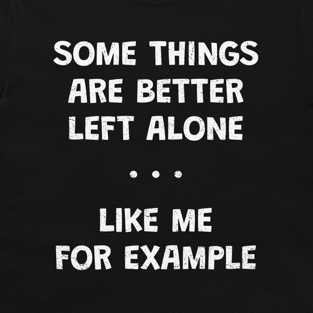 A close-up of a black garment, likely a t-shirt, featuring a distressed white typographic print that reads 'SOME THINGS ARE BETTER LEFT ALONE. LIKE ME FOR EXAMPLE'.