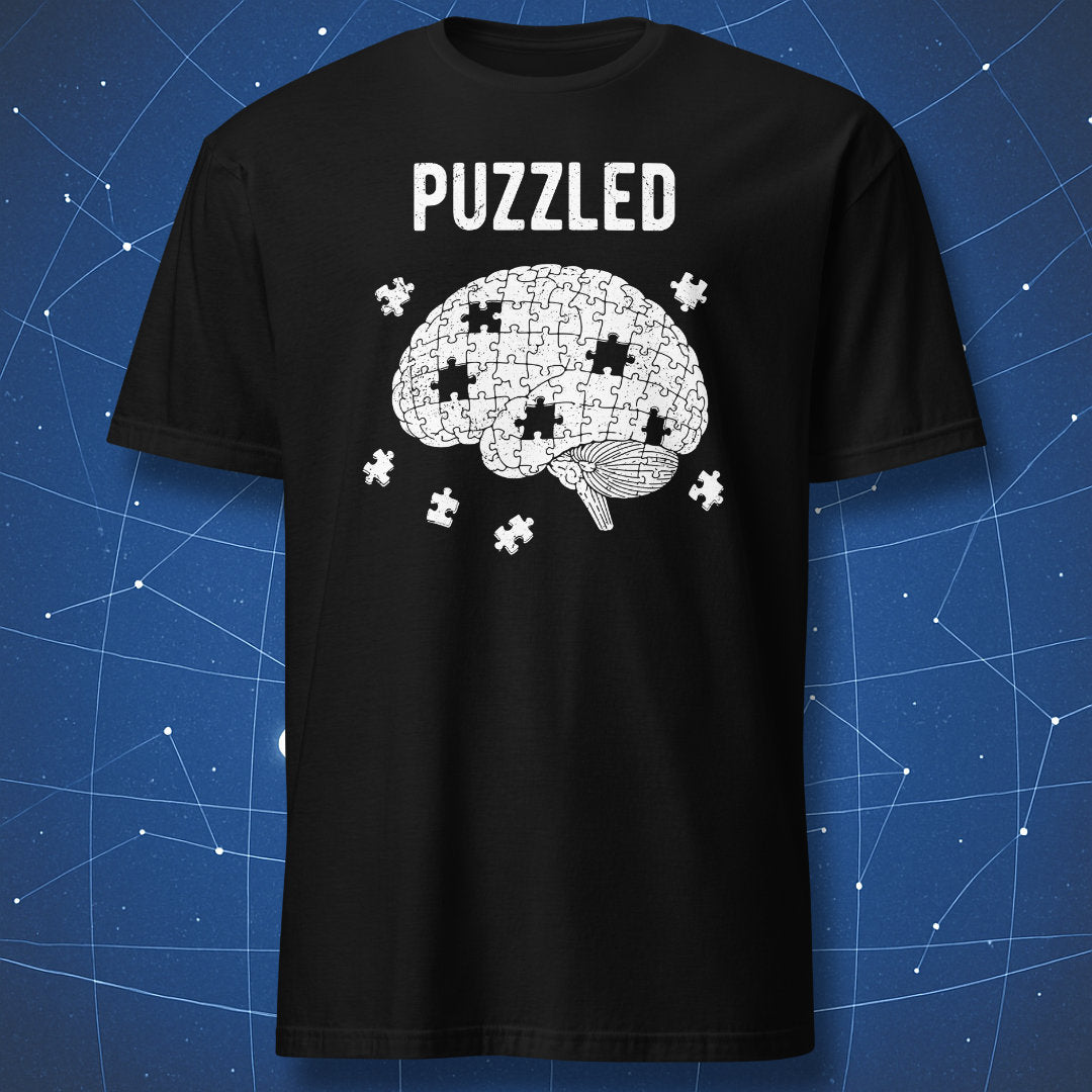 white puzzle brain t-shirt design with scattered pieces and “Puzzled” text on black shirt
