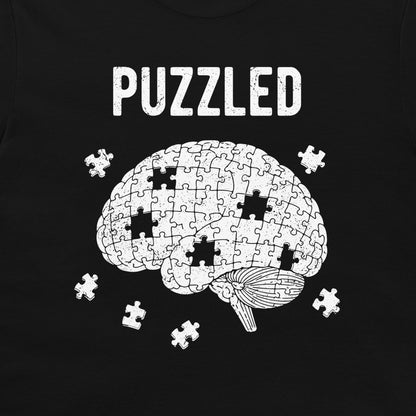 A black t-shirt featuring a white graphic of a brain made of puzzle pieces with several missing pieces, under the word 'PUZZLED' in a distressed white font.
