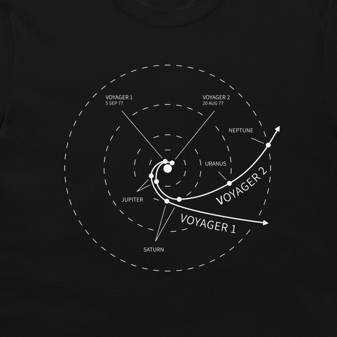 A black t-shirt featuring a white printed graphic of the Voyager 1 and Voyager 2 spacecraft trajectories relative to the outer planets, with labels for Uranus, Neptune, Jupiter, Saturn, and the Sun.