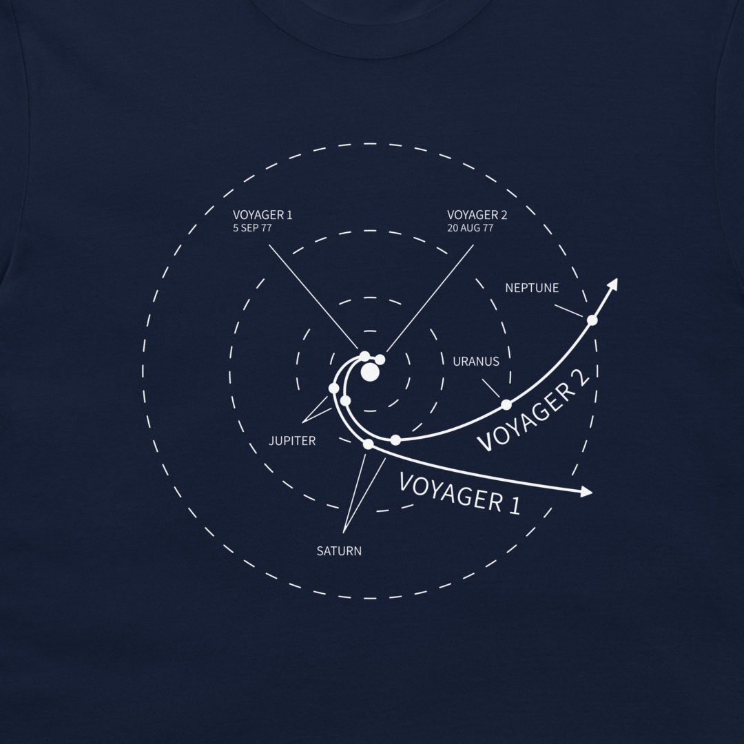 A close-up of a navy blue t-shirt featuring a white printed graphic of Voyager 2's orbit with labeled planets and spacecraft trajectories.