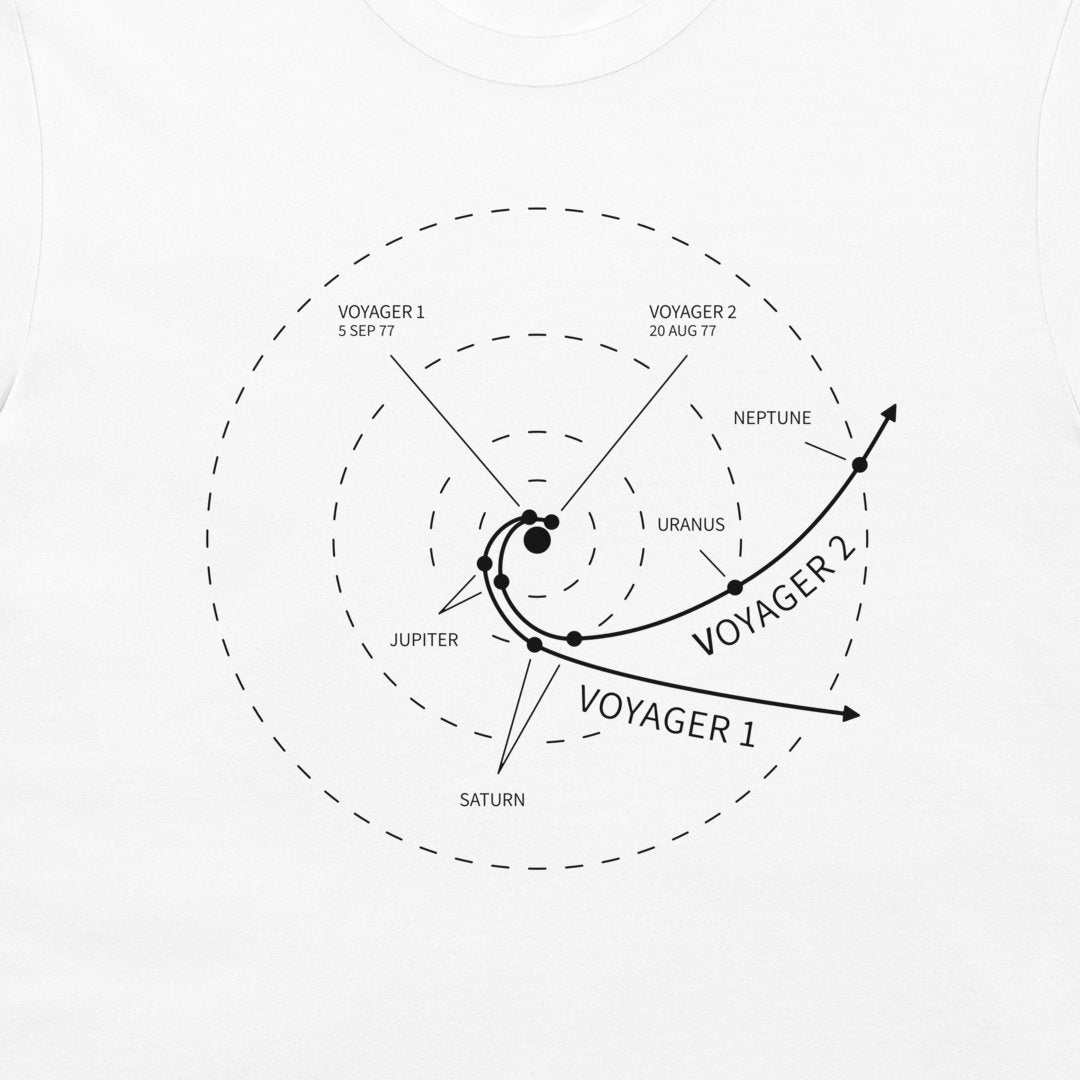 A white crewneck t-shirt featuring a black printed graphic of Voyager 1 and Voyager 2 spacecraft trajectories relative to the solar system planets, including Jupiter, Saturn, Uranus, Neptune, and the Sun.