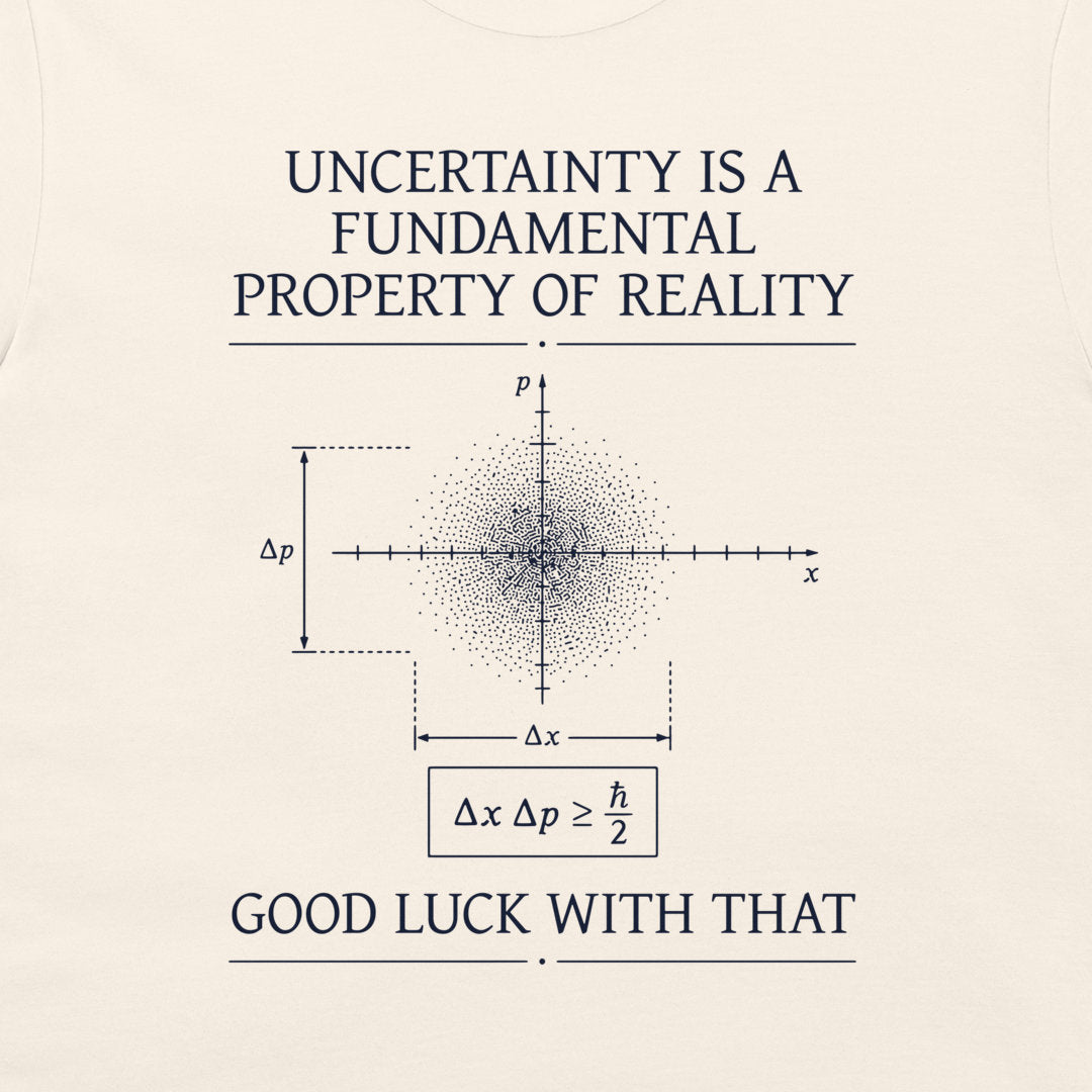 A cream-colored graphic t-shirt featuring white text and a physics diagram. The text reads 'UNCERTAINTY IS A FUNDAMENTAL PROPERTY OF REALITY' at the top and 'GOOD LUCK WITH THAT' at the bottom, surrounding a central uncertainty principle diagram.