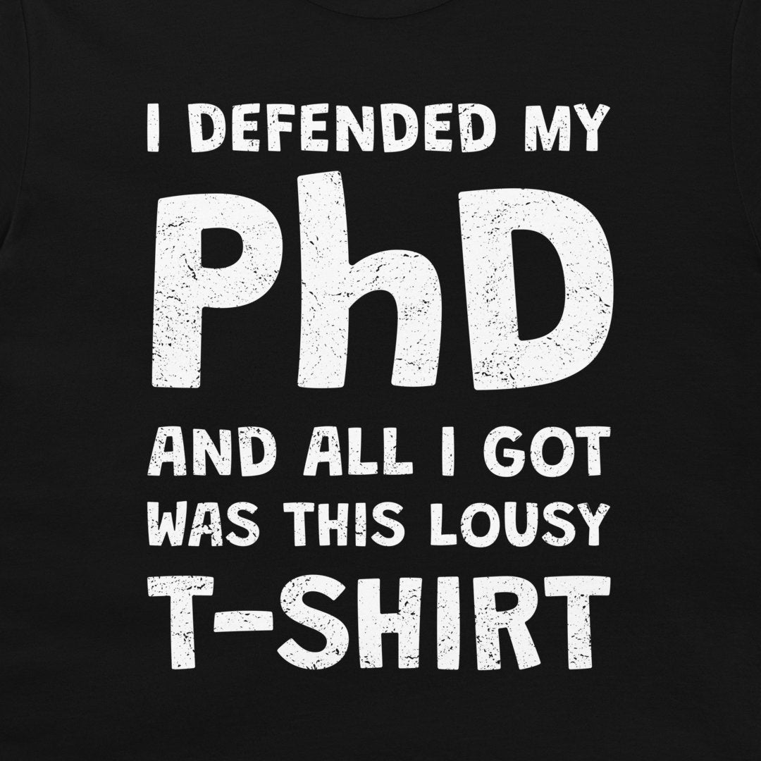 A close-up of a black T-shirt with a distressed white graphic print that reads, 'I DEFENDED MY PhD AND ALL I GOT WAS THIS LOUSY T-SHIRT'.