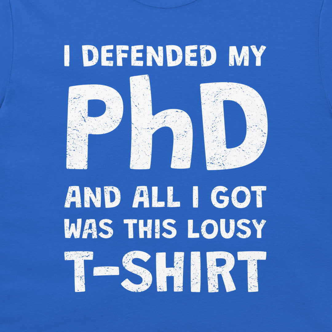 A close-up of a royal blue T-shirt with a distressed white graphic text that reads 'I DEFENDED MY PhD AND ALL I GOT WAS THIS LOUSY T-SHIRT'.