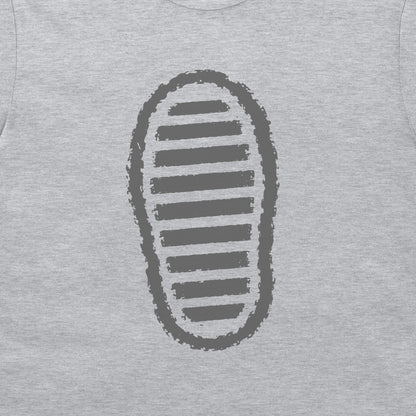 A close-up of a grey t-shirt, featuring a dark grey graphic print of a shoe sole with horizontal stripes.