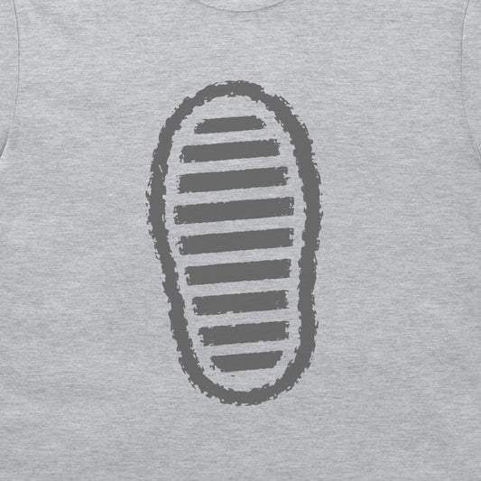A close-up of a grey t-shirt, featuring a dark grey graphic print of a shoe sole with horizontal stripes.