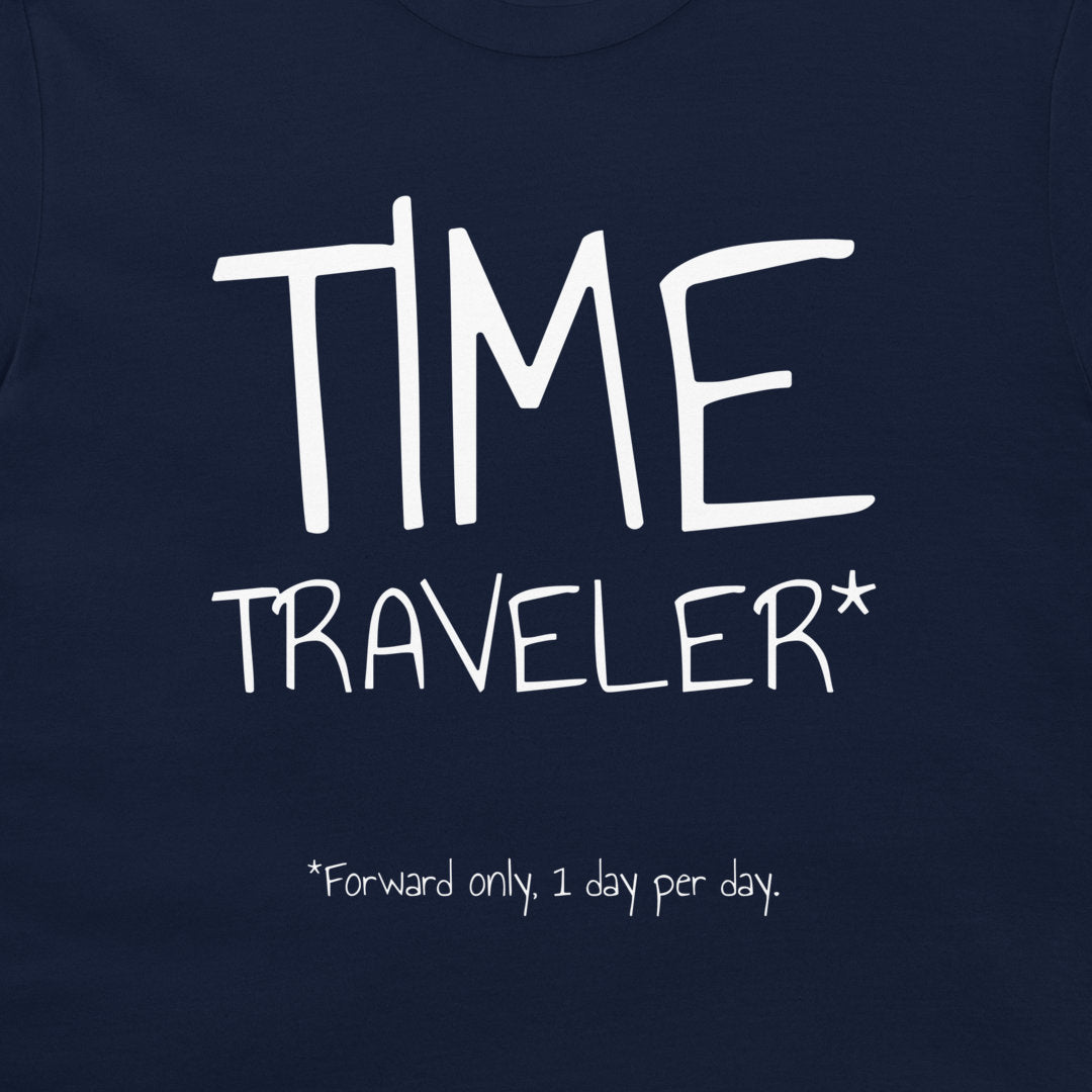 Close-up of a navy blue t-shirt featuring a white graphic print that reads 'TIME TRAVELER*' with the note '*Forward only, 1 day per day.'.