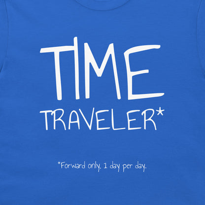 A close-up of a blue t-shirt featuring a white graphic print that reads 'TIME TRAVELER*' with the note '*Forward only, 1 day per day.' printed below.