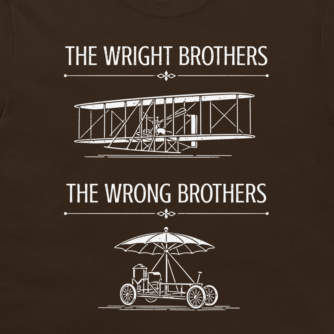 A dark brown t-shirt featuring a white graphic print with the text 'THE WRIGHT BROTHERS' above a line drawing of a vintage biplane, and 'THE WRONG BROTHERS' below a line drawing of an early automobile with an umbrella.