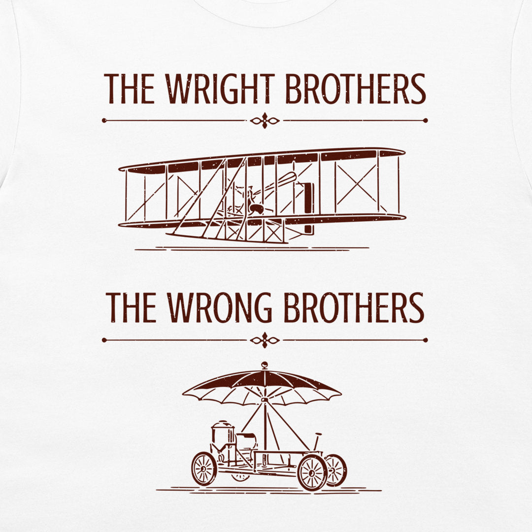 A white t-shirt featuring a red-brown graphic print with the text 'THE WRIGHT BROTHERS' above a line drawing of a vintage biplane, and 'THE WRONG BROTHERS' below a line drawing of an early automobile with an umbrella.