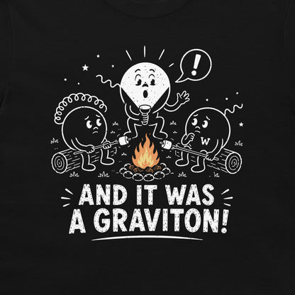 A black t-shirt featuring a white hand-drawn style graphic of three cartoon particle characters roasting marshmallows over a campfire, with the text 'AND IT WAS A GRAVITON!' printed below.