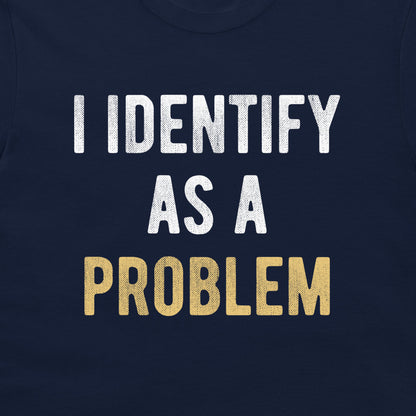 A close-up of a navy blue t-shirt featuring a distressed text graphic that reads 'I IDENTIFY AS A PROBLEM' in white and gold lettering.