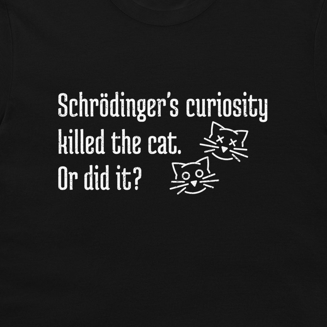 A close-up of a black t-shirt featuring a white graphic print with the text 'Schrödinger's curiosity killed the cat. Or did it?' and two simple line-art cat faces, dead and alive.