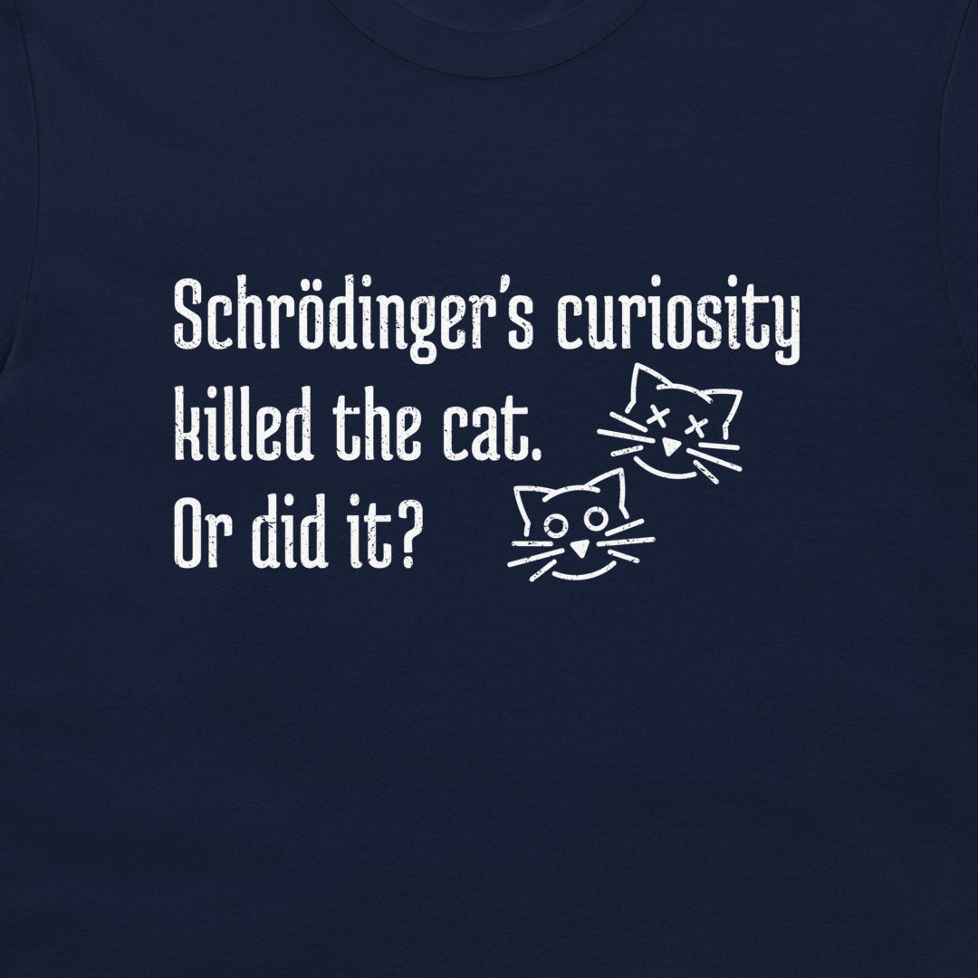 A close-up of a navy blue t-shirt featuring a white printed graphic with the text 'Schrödinger's curiosity killed the cat. Or did it?' and two simple line-art cat faces, one alive and one with X's for eyes.