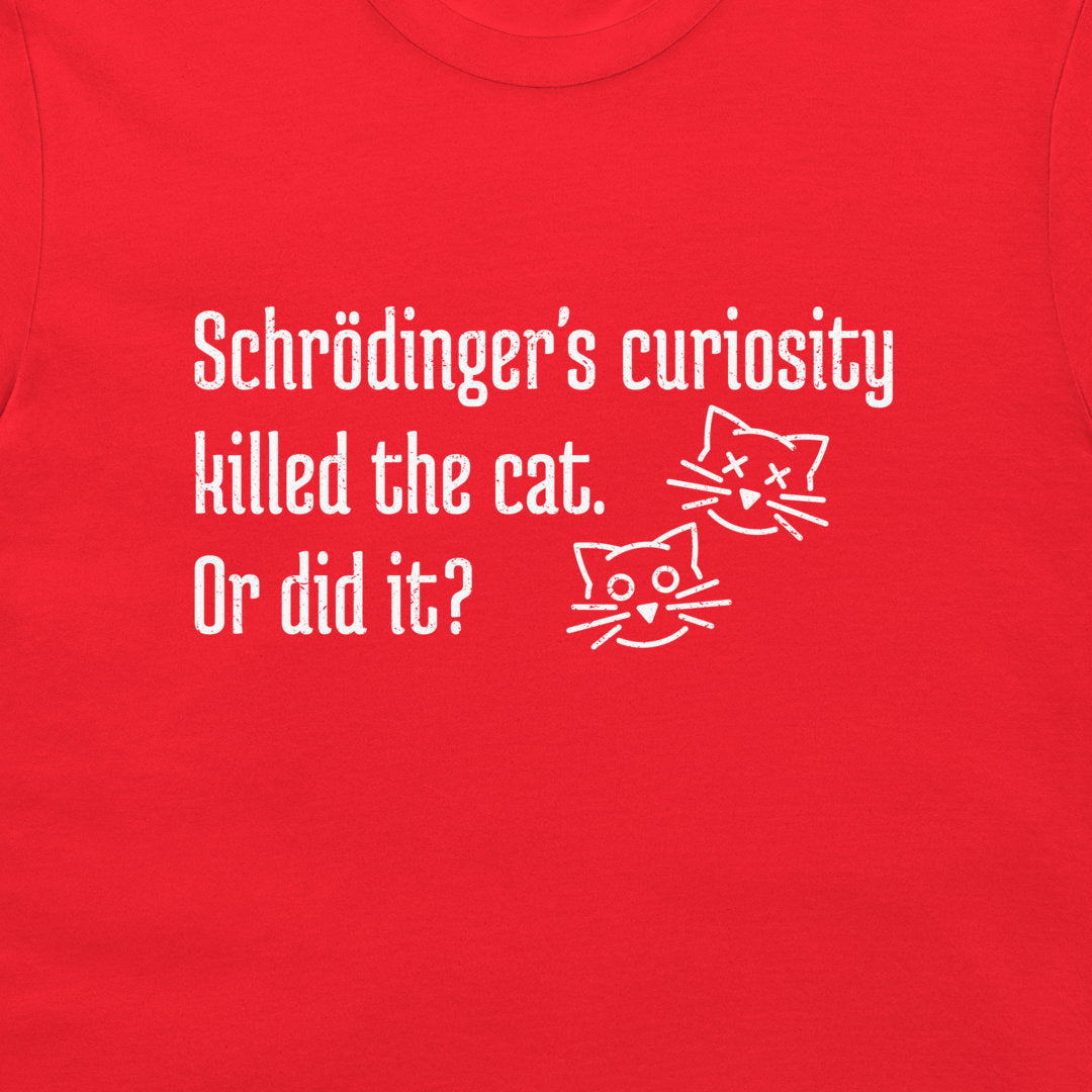 A close-up of a red t-shirt featuring a white graphic print with the text 'Schrödinger's curiosity killed the cat. Or did it?' and two simple line-art cat faces, dead and alive.