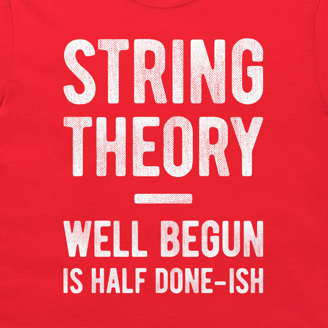 A close-up of a red garment, likely a t-shirt, featuring a distressed white graphic print that reads 'STRING THEORY WELL BEGUN IS HALF DONE-ISH'.