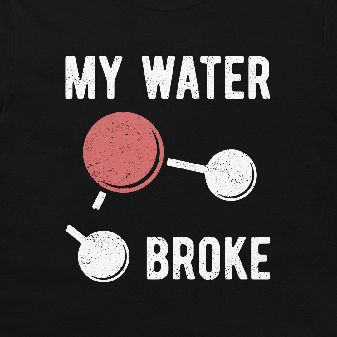 A close-up of a blackt-shirt featuring a distressed graphic print that reads 'MY WATER BROKE' with a broken water molecule illustration in white and red.