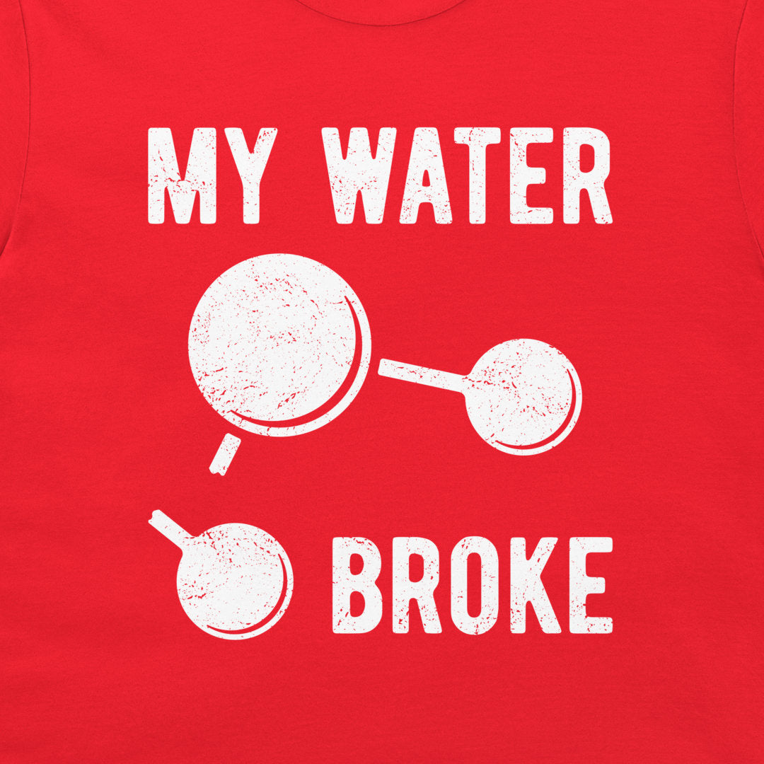 A close-up of a red t-shirt featuring a distressed graphic print that reads 'MY WATER BROKE' with a broken water molecule illustration in white.