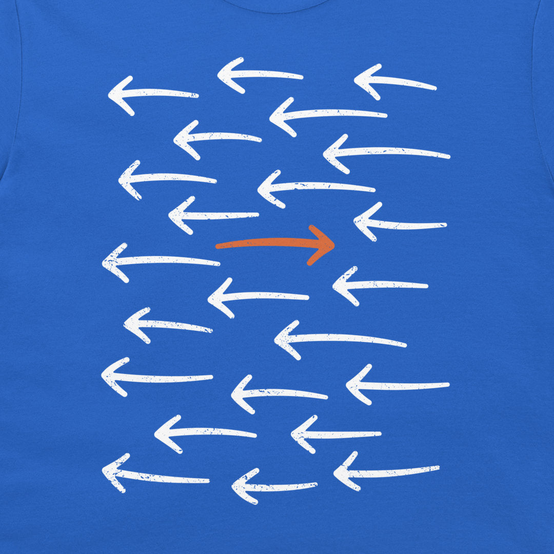 A close-up of a royal blue t-shirt featuring a graphic print of multiple white chalk-style arrows pointing left, with one prominent orange arrow pointing right in the center.