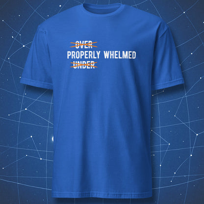 A royal blue short-sleeve crewneck t-shirt with a graphic text print reading 'OVER PROPERLY WHELMED UNDER' in white and orange, displayed against a dark blue starry space background.