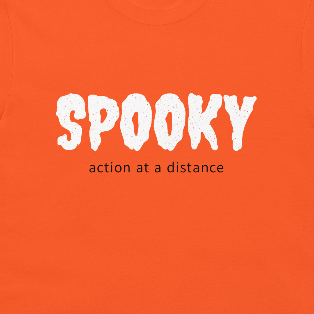 Close-up of white SPOOKY lettering and black action at a distance text on an orange T-shirt.